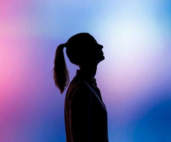 Silhouette of a person in a serene yoga pose against a teal background.